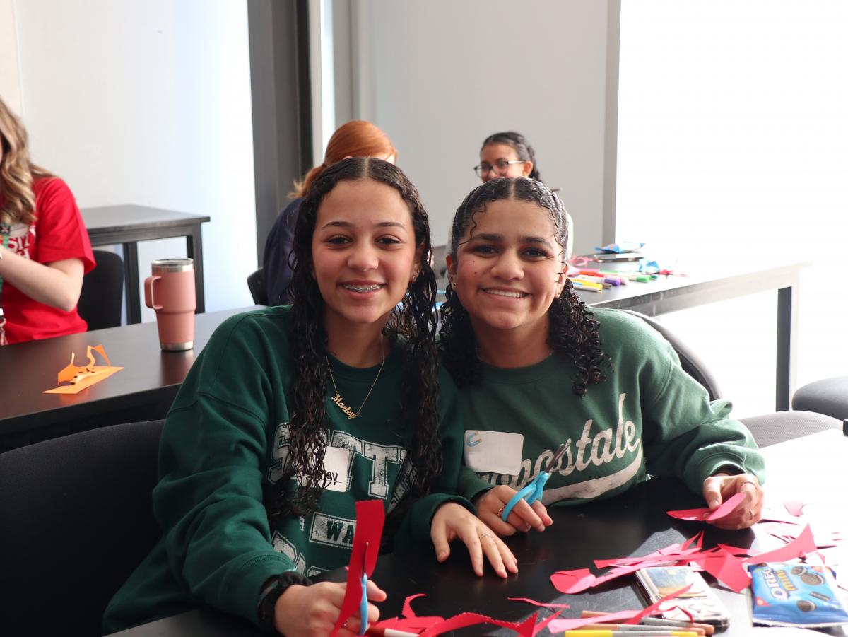 Two girls smiling with construction paper and scissors